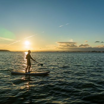 Man paddleboarding at sunset