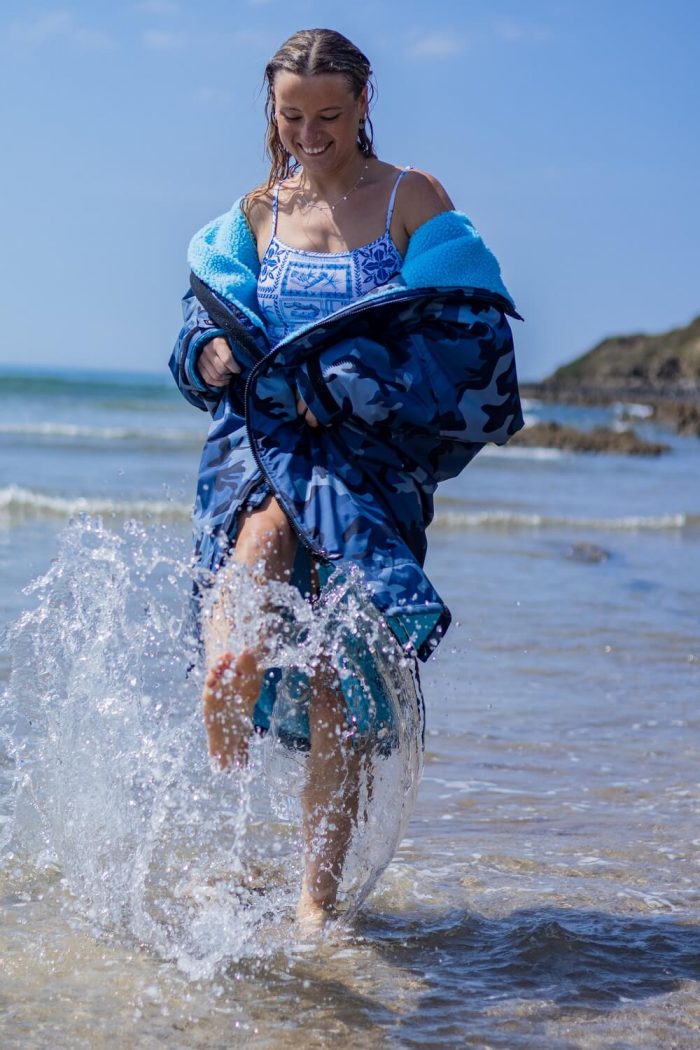 Woman splashing sea water in her blue camo Dryrobe.