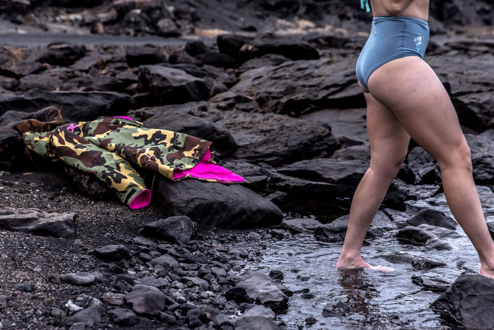 Can you wash a Dryrobe? Girl stepping into the sea leaving her pink and green camo Dryrobe on the shore.