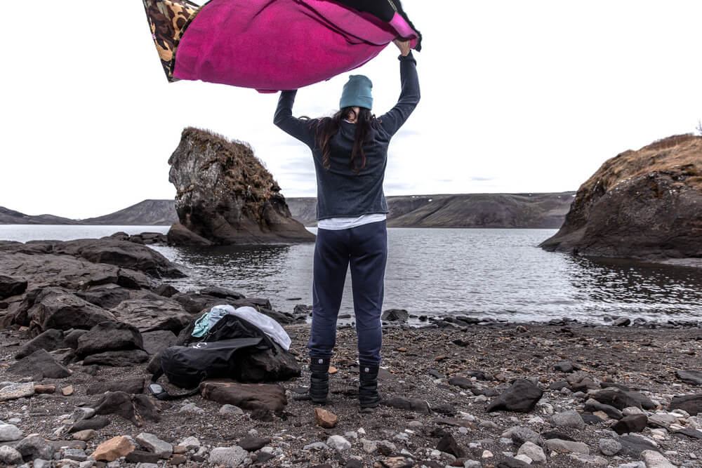 How to dry a Dryrobe. Woman air-drying her Dryrobe Advance on the shore.