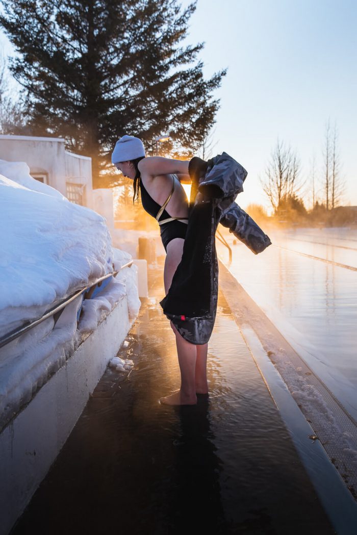 Do you put a Dryrobe on when wet? Woman keeping warm while having a dip in an ice bath.